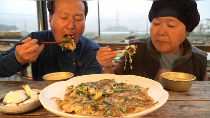 爸爸妈妈在下雨天吃煎饼配米酒，一口煎饼一口酒，真是惬意！