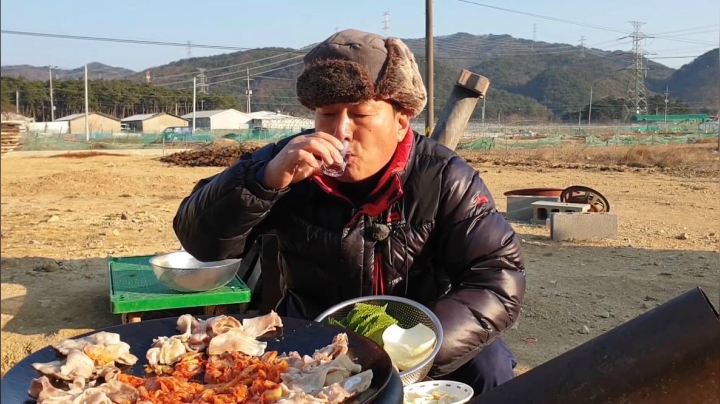 爸爸在锅盖上烤五花肉，边烤边吃，再配上一瓶烧酒，美滋滋！