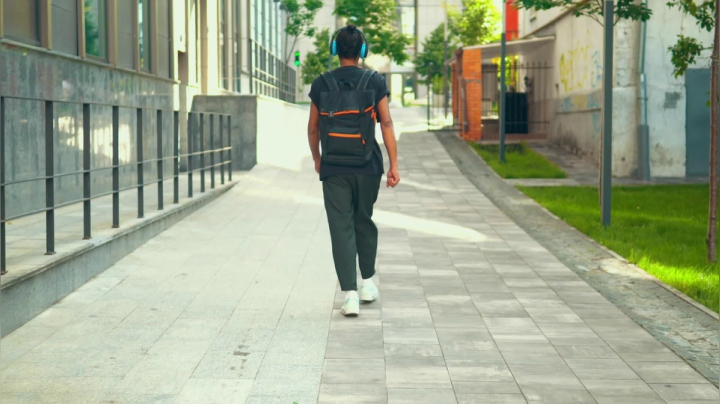 mixkit-boy-walking-happily-down-the-street-with-headphones-4889