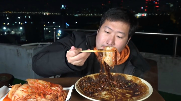 一人在户外吃温暖浓郁的炸酱面，搭配泡菜，香的把嘴都烫住了！